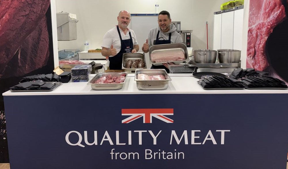 Two men holding trays of meat at a Quality Meat from Britain stand.